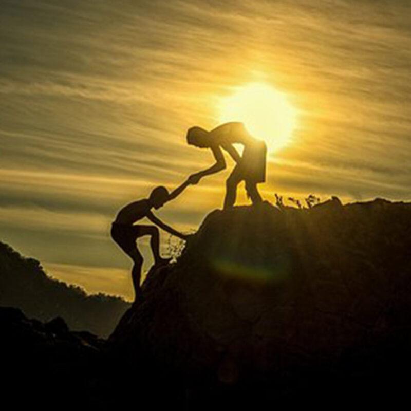 Helping Another to the Top of a Hill at Sundown