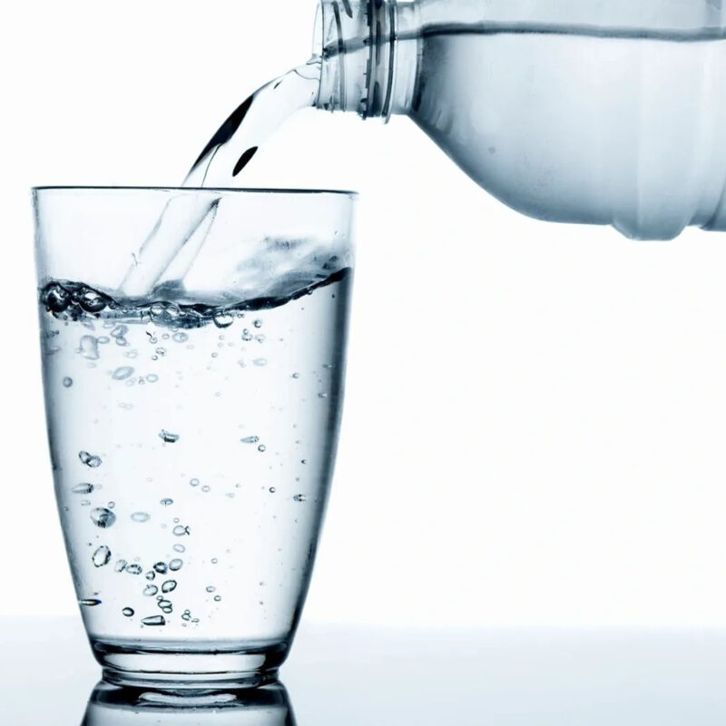 Water Pouring from Bottle into a Clear Glass