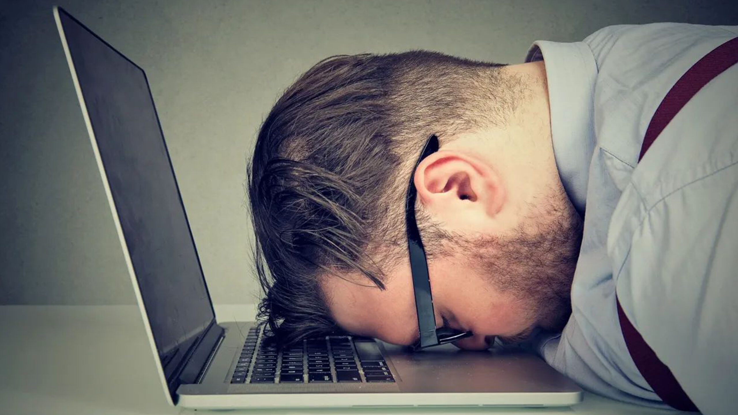 exhausted man asleep with head on laptop