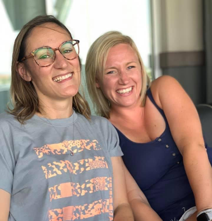 Two Women Sitting Next to Each Other Smiling and Laughing