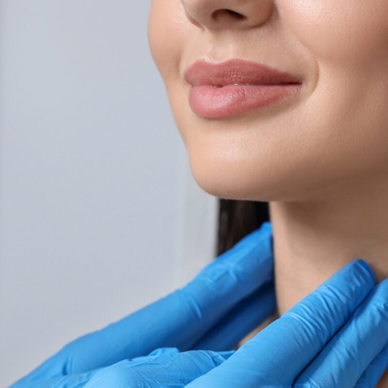 Woman's Neck Being Inspected By Doctor's hands Wearing Blue Gloves